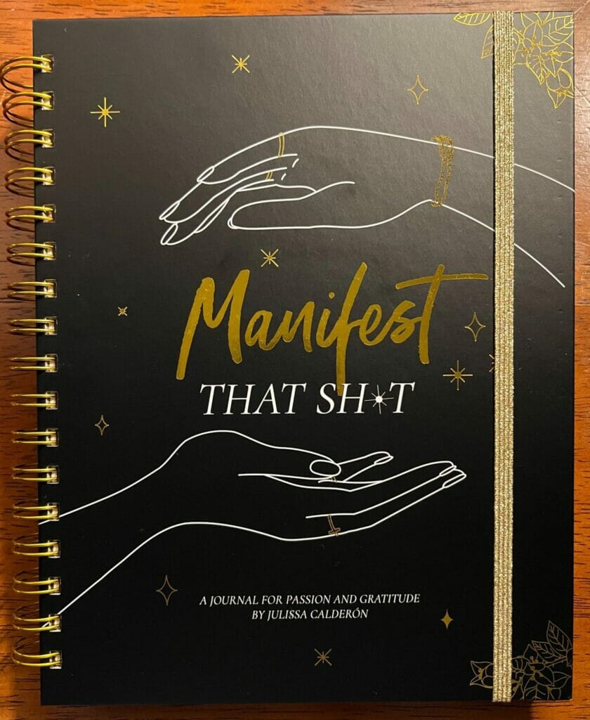 Journal with a black cover showing the text “Manifest that sh*t”